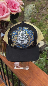 One of a kind, hand painted Black & Tan trucker hat with a Ouija Planchette painted is, golds, blues, white & blacks.  