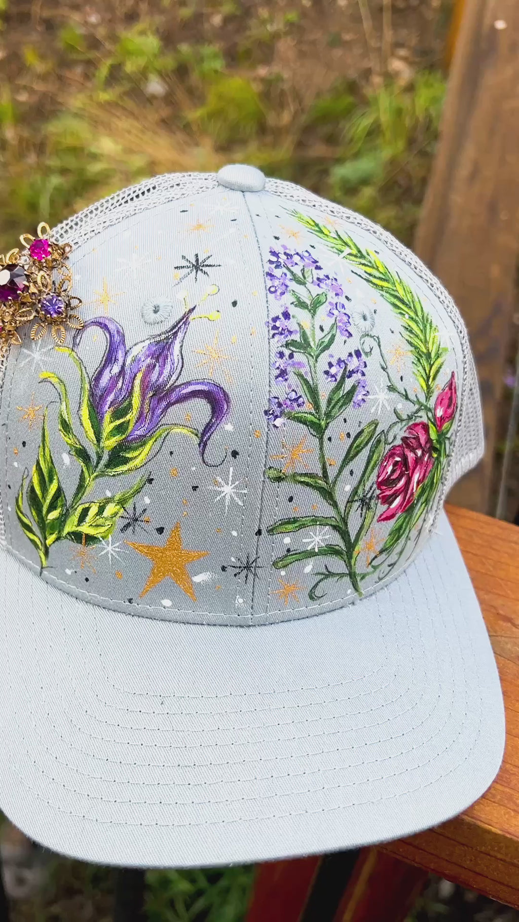 "Aunt Jet's Garden" hand painted gray truck hat.  Inspired by the book Practical Magic.  Hand Painted belladonna, rosemary, red roses, lavender with stars.  Accented with a vintage rhinestone brooch with deep purple and fuschia stones.